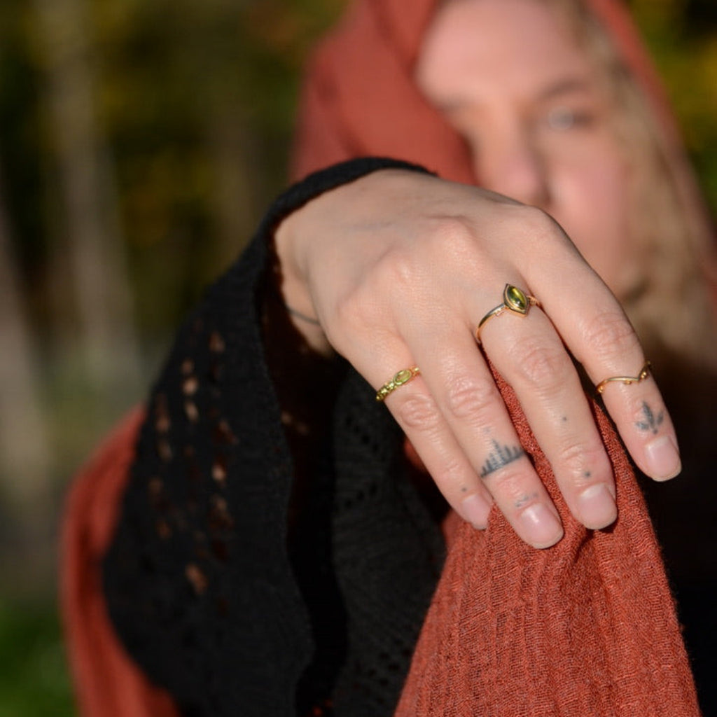 Person wearing multiple gold rings with a blurred natural background
