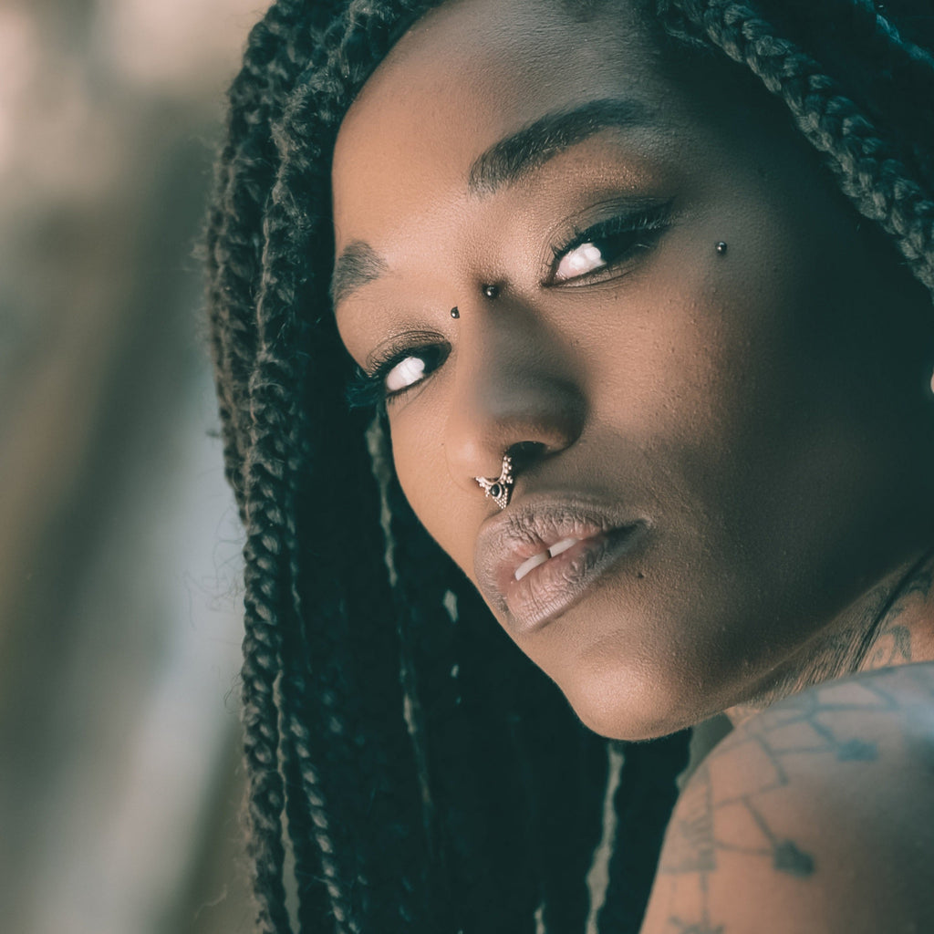 model wearing a silver septum nose ring with black gemstone.