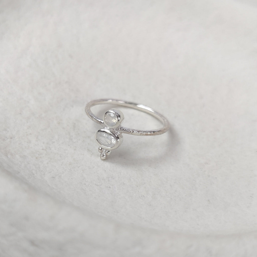 Silver ring with small moonstones on a textured white surface