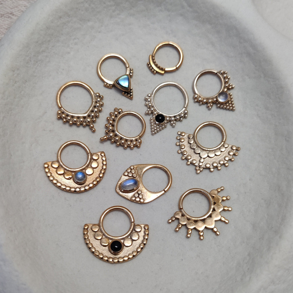 Collection of solid gold septum jewelry, displayed on a jewelry plate. Design by Noomaad.