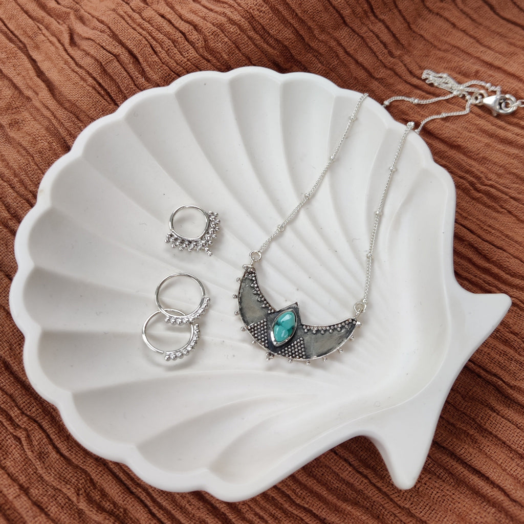 sterling silver necklace, septum and tiny hoop earrings on a jewelry dish