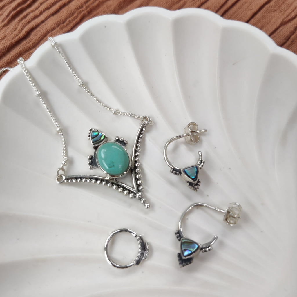detailshot of turquoise necklace, abalone shell stud earrings and septum