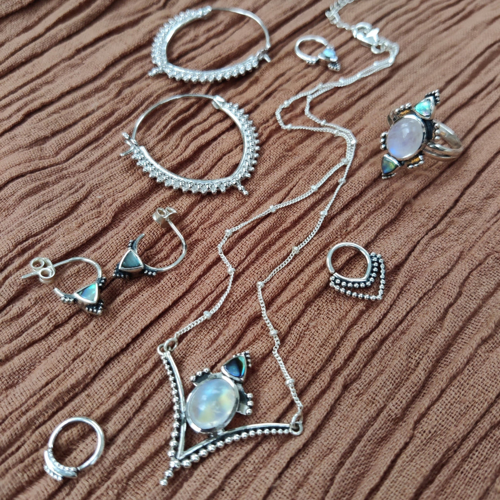 jewelry flatlay, moonstone and sterling silver necklace, earrings, ring and septum