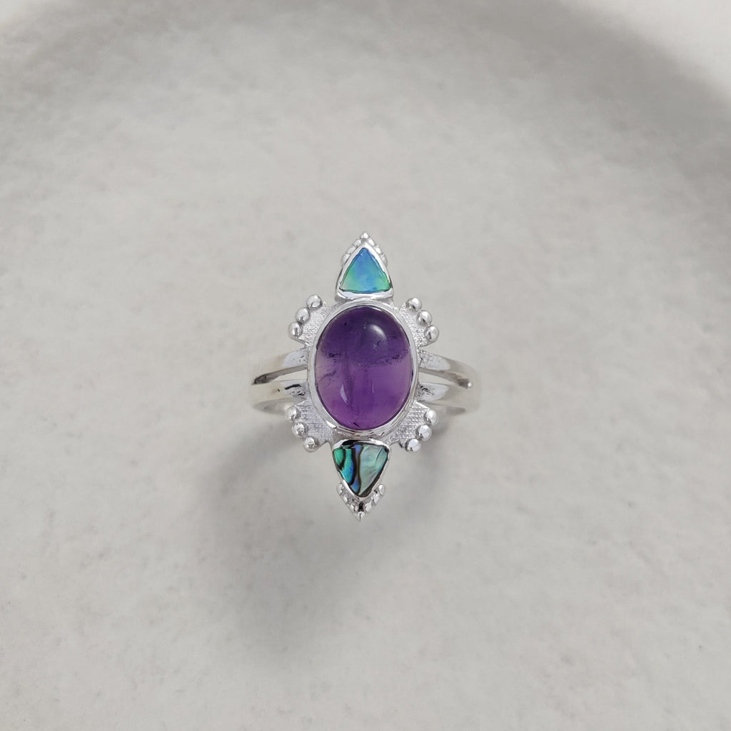 Silver ring with purple gemstone on a white dish