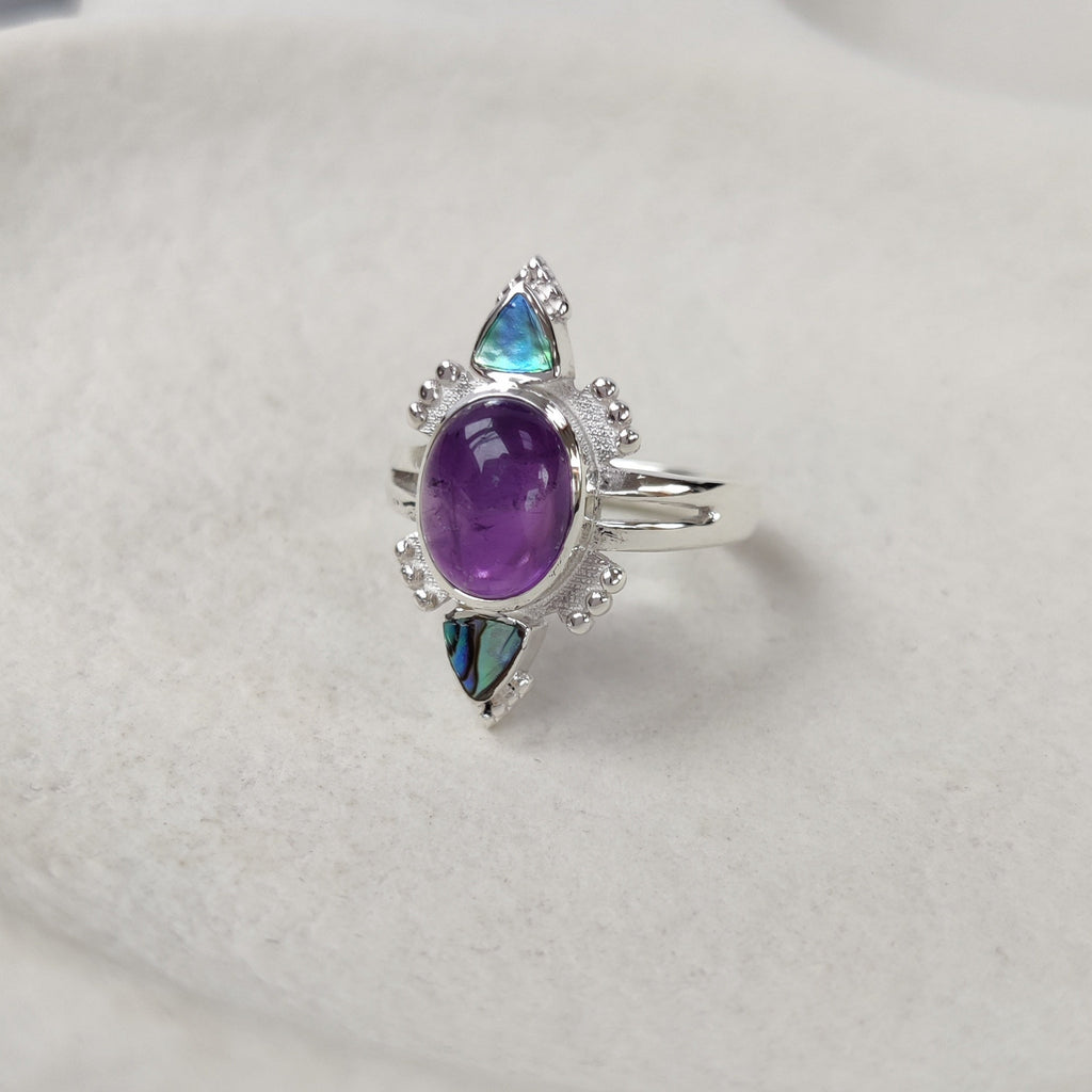 Silver ring with purple gemstone on a white surface