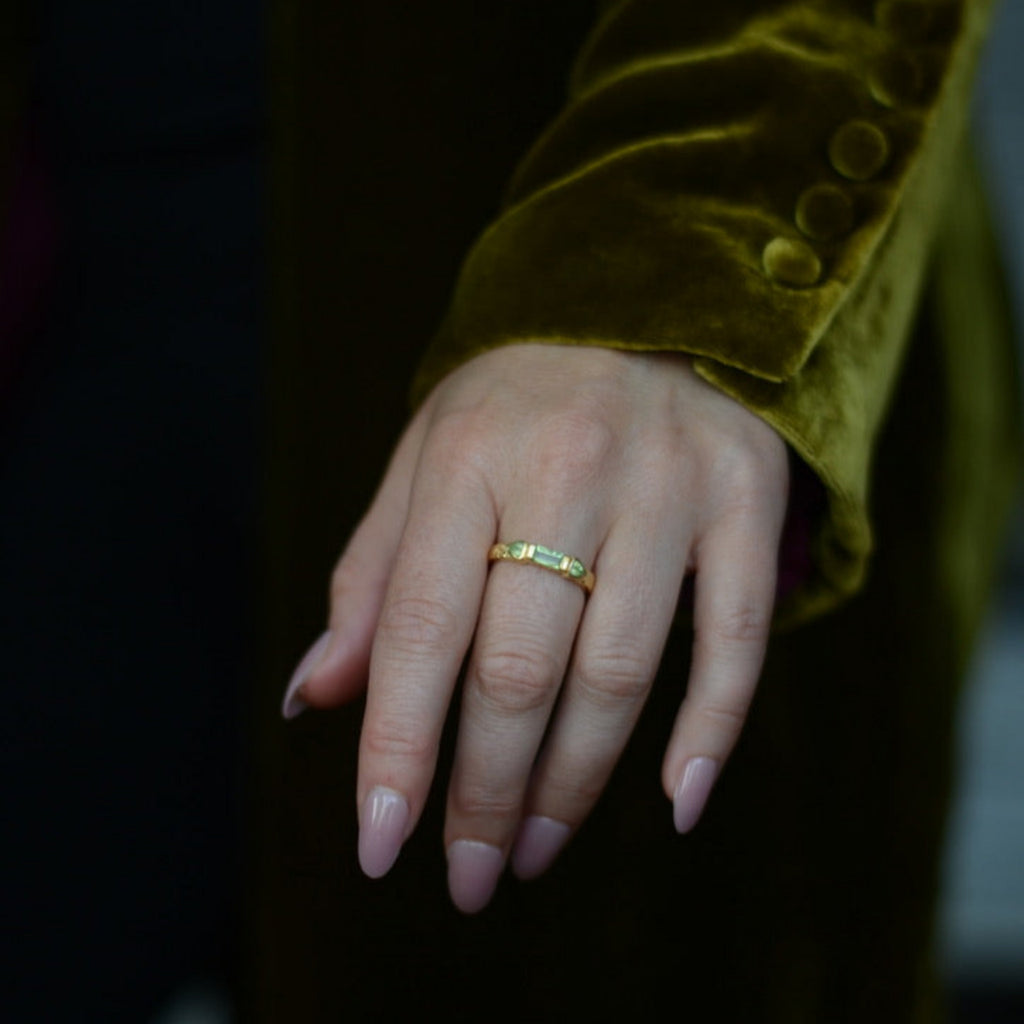 Close-up of a hand wearing a three stone gold ring with a blurred background
