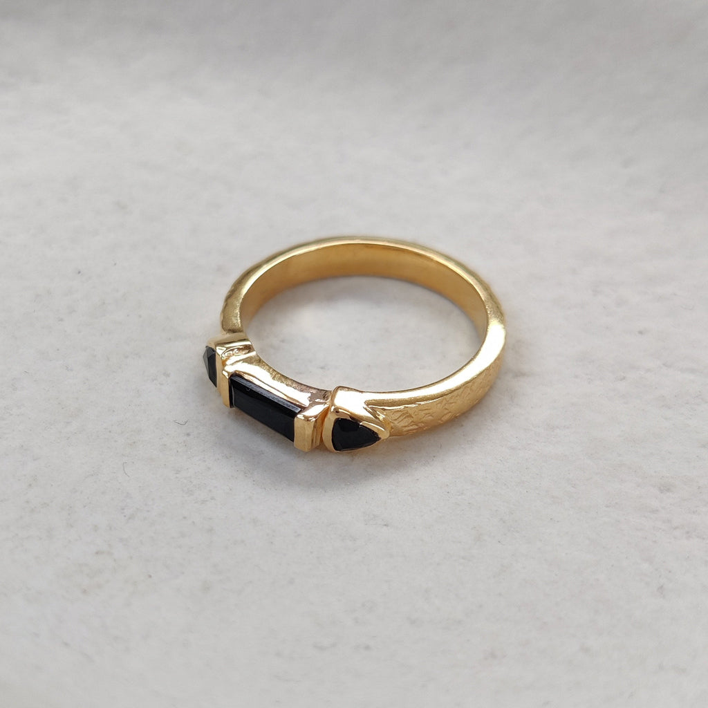 Gold ring with a black gemstones on a light background