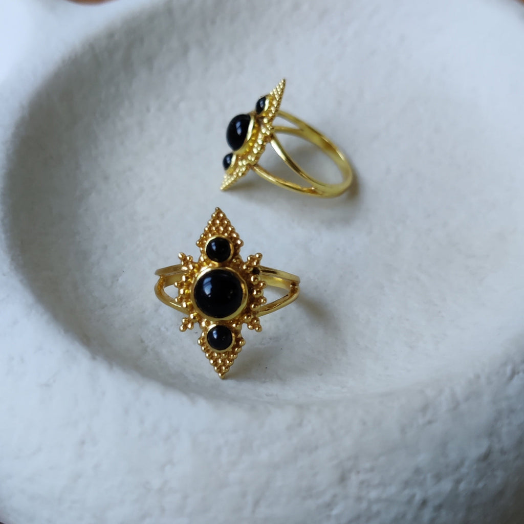 Brass rings with black onyx, displayed on a jewelry plate.