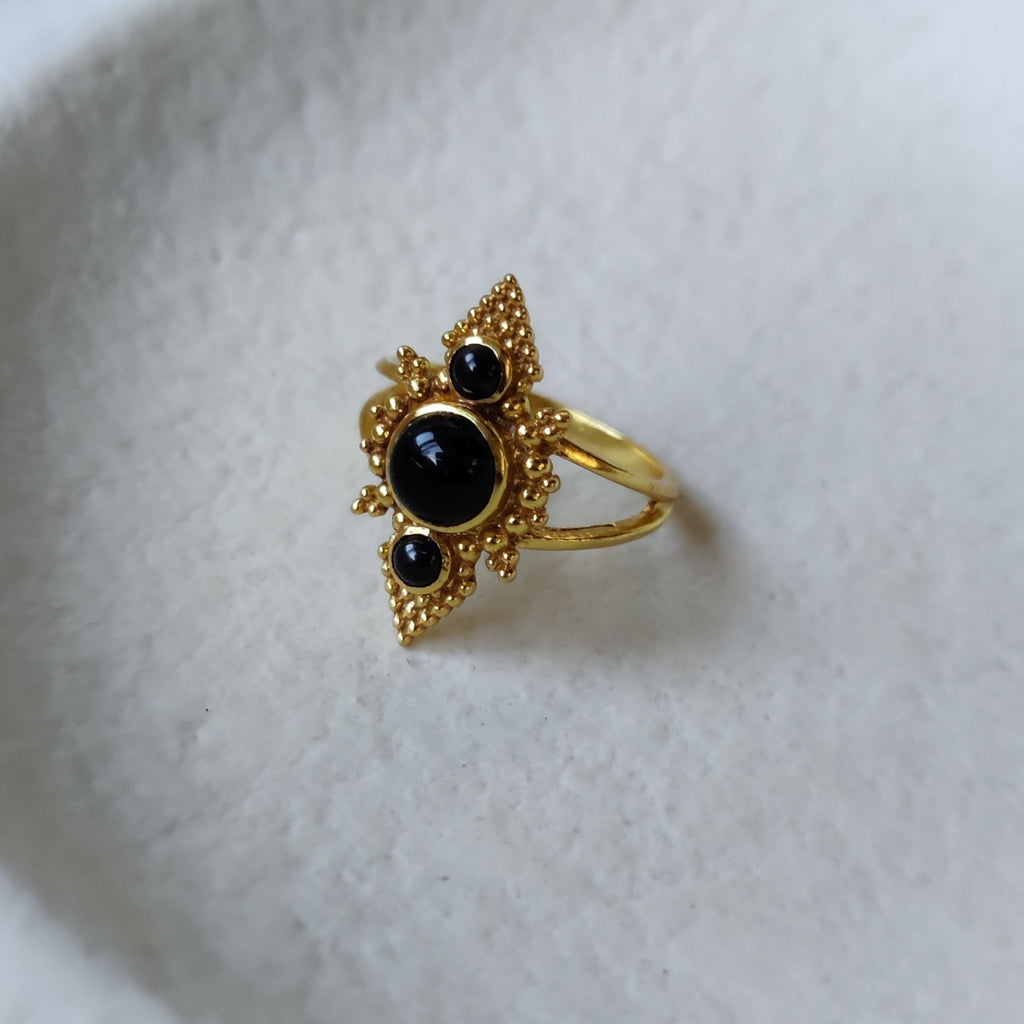 Brass rings with black onyx, displayed on a jewelry plate.