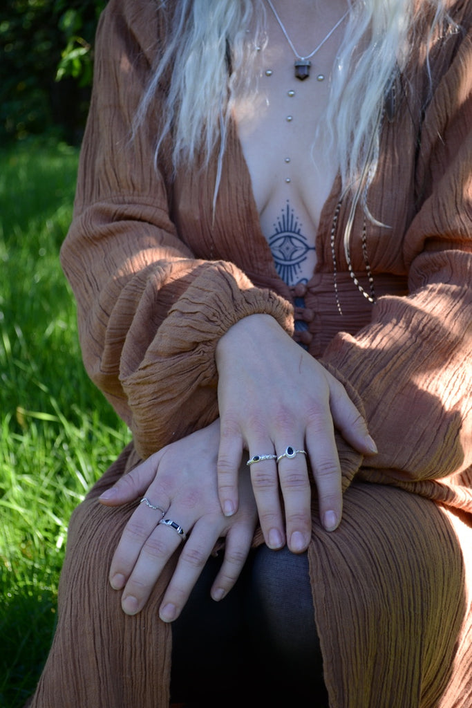 Person wearing rings with a tattoo on chest sitting outdoors