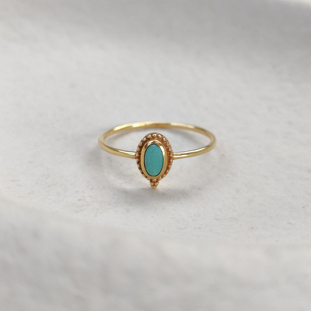 Gold ring with a turquoise stone on a white surface
