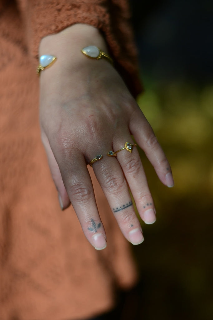 Hand wearing multiple gold rings with blue topaz gemstones