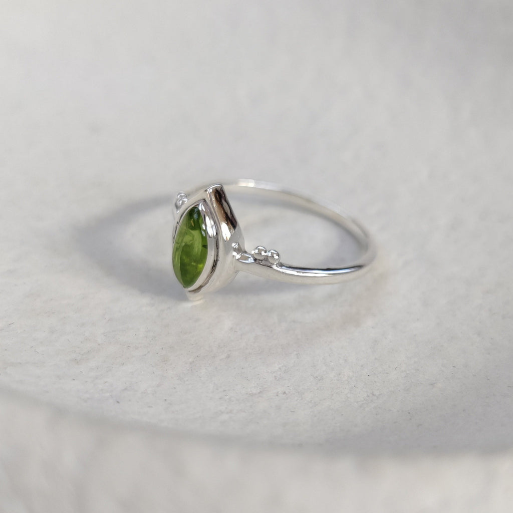 Silver ring with a green gemstone on a white background