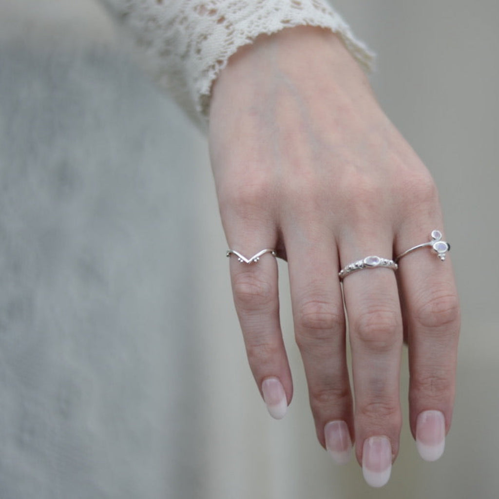 Hand wearing multiple silver rings with a blurred background.