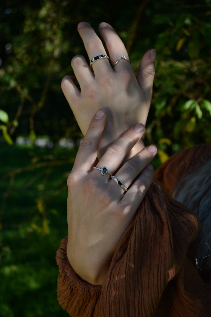 Close-up of two hands with rings against a blurred green background