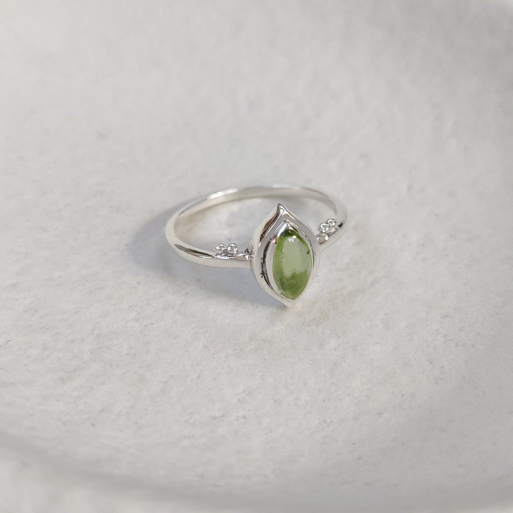 Silver ring with a green peridot gemstone on a white background