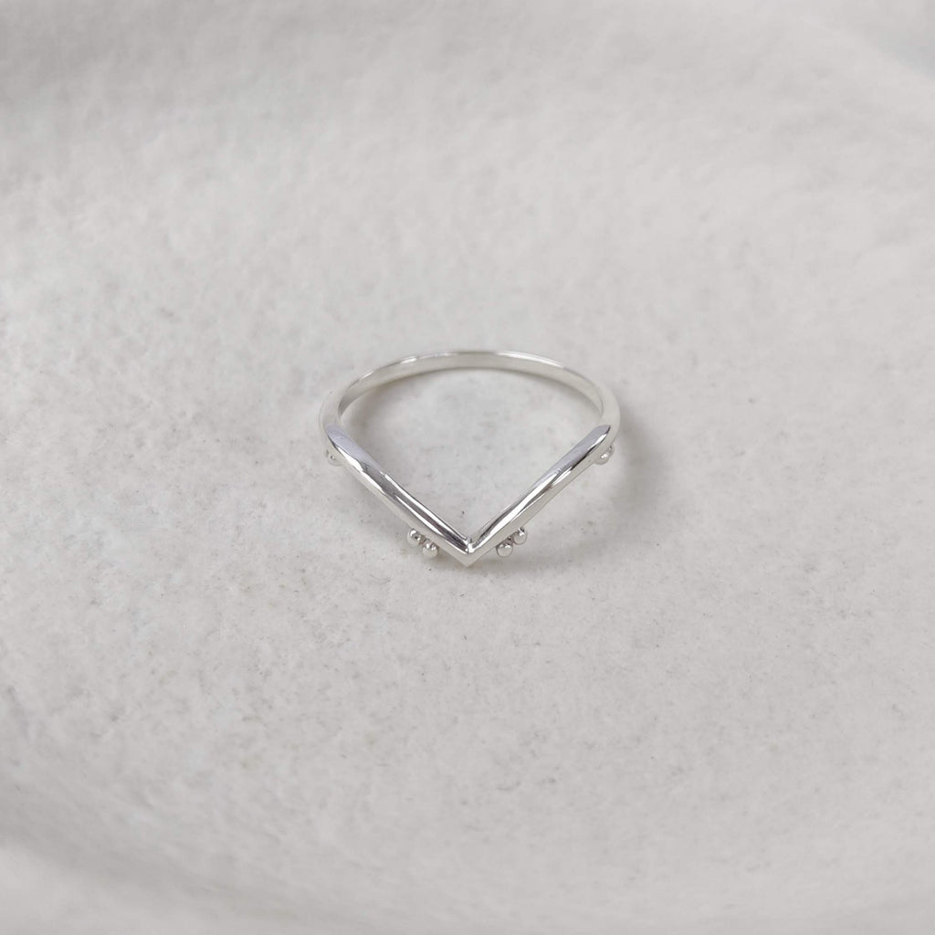 Chevron silver ring on a textured white surface.