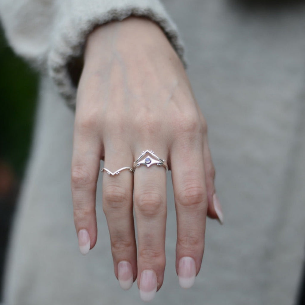 Hand wearing three rings with a blurred background.