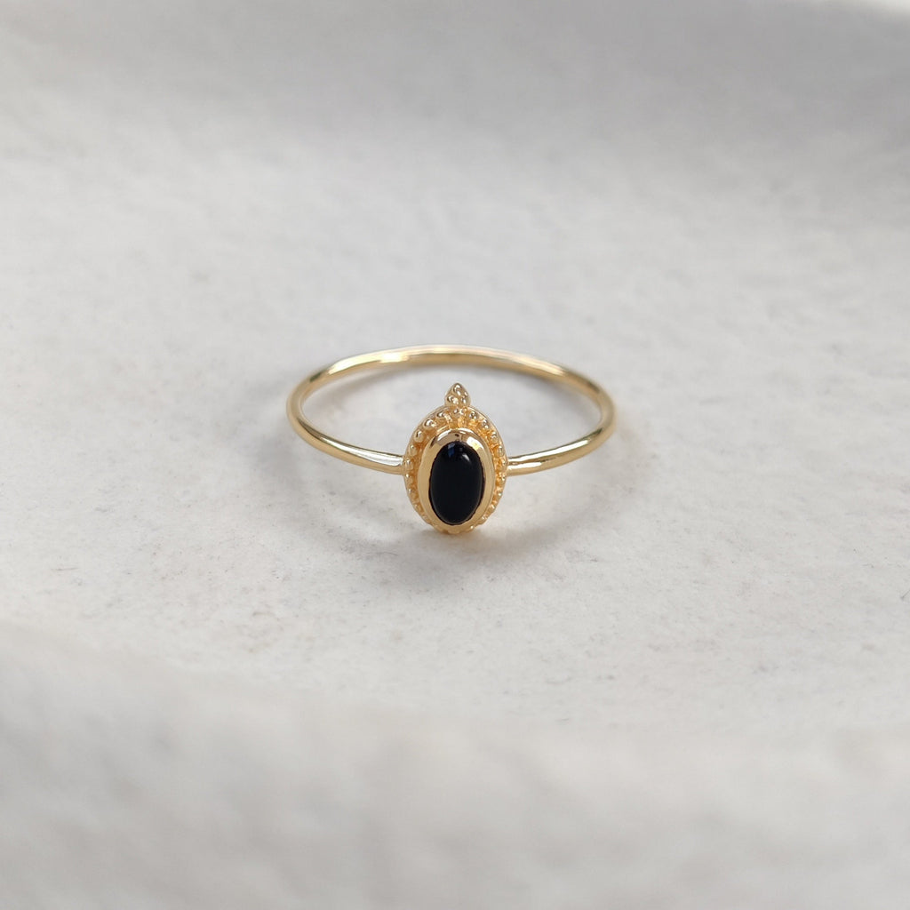 Gold ring with a black gemstone on a white surface