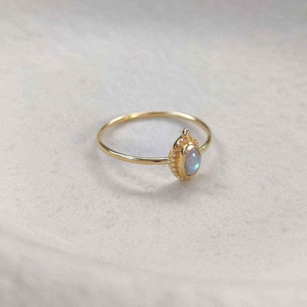 Gold ring with a moonstone on a white background.