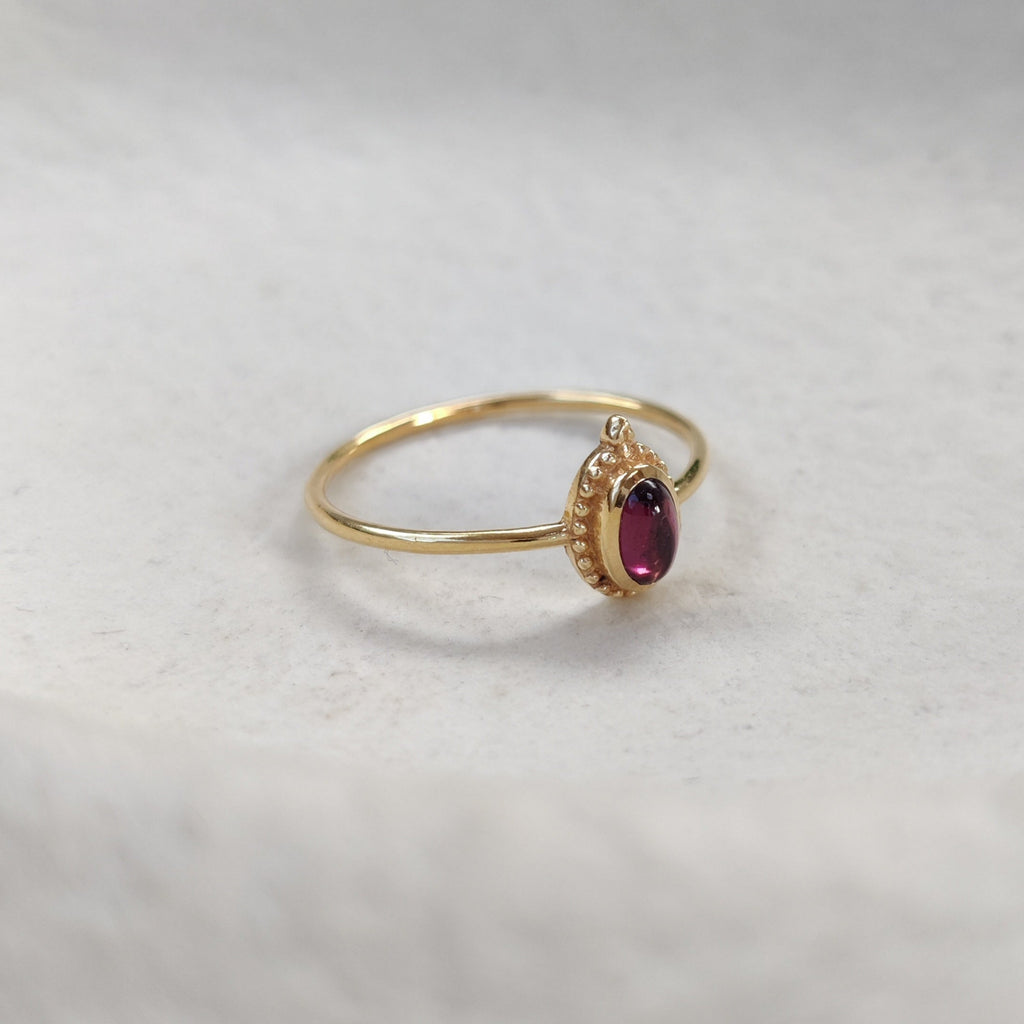 Gold ring with a red gemstone on a white background