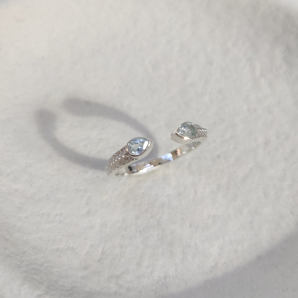 Open cuff silver ring with a two gemstones on a white background