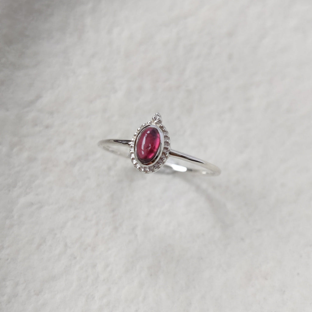 Dainty silver ring with garnet gemstone on white background