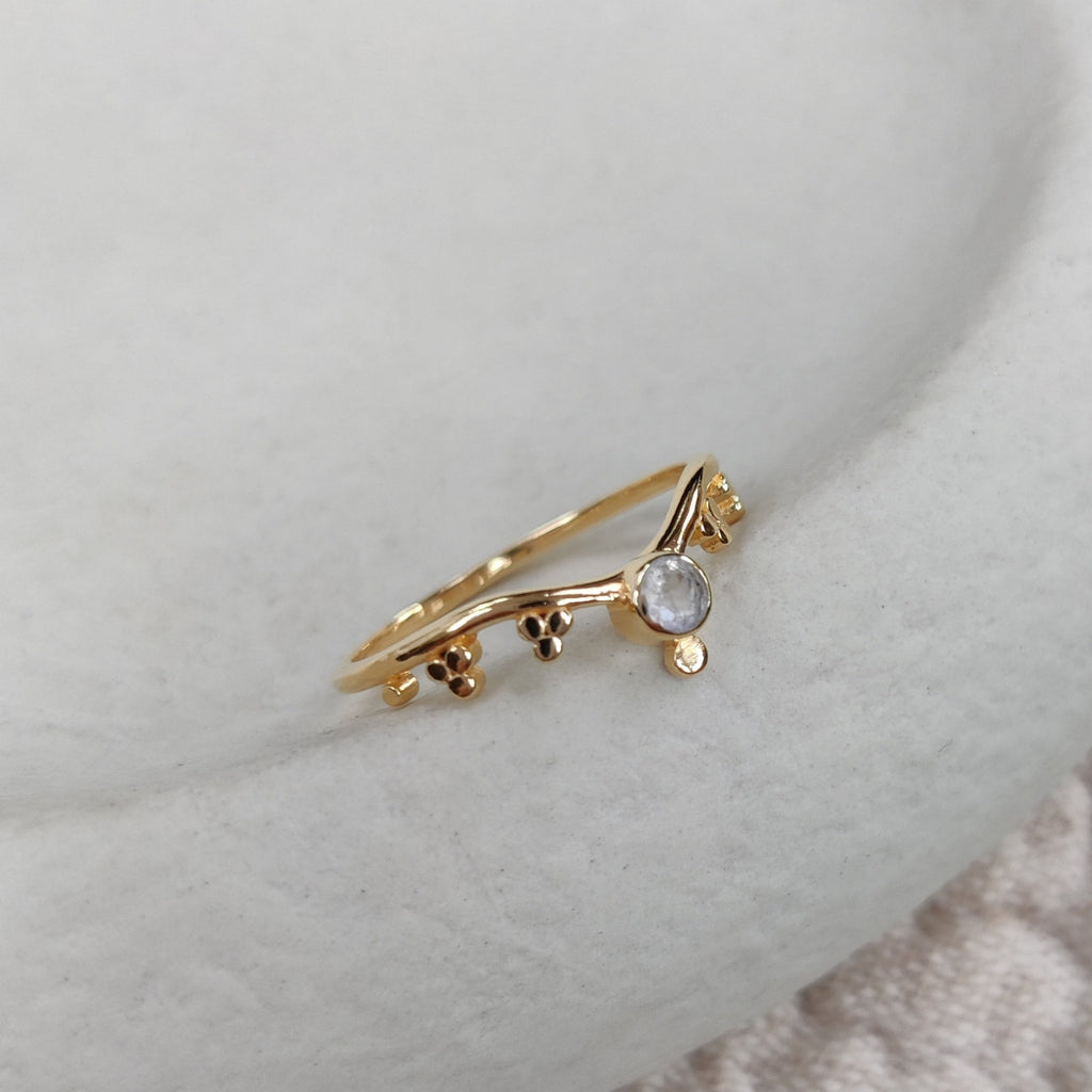 Gold ring with a small moonstone on a light surface.