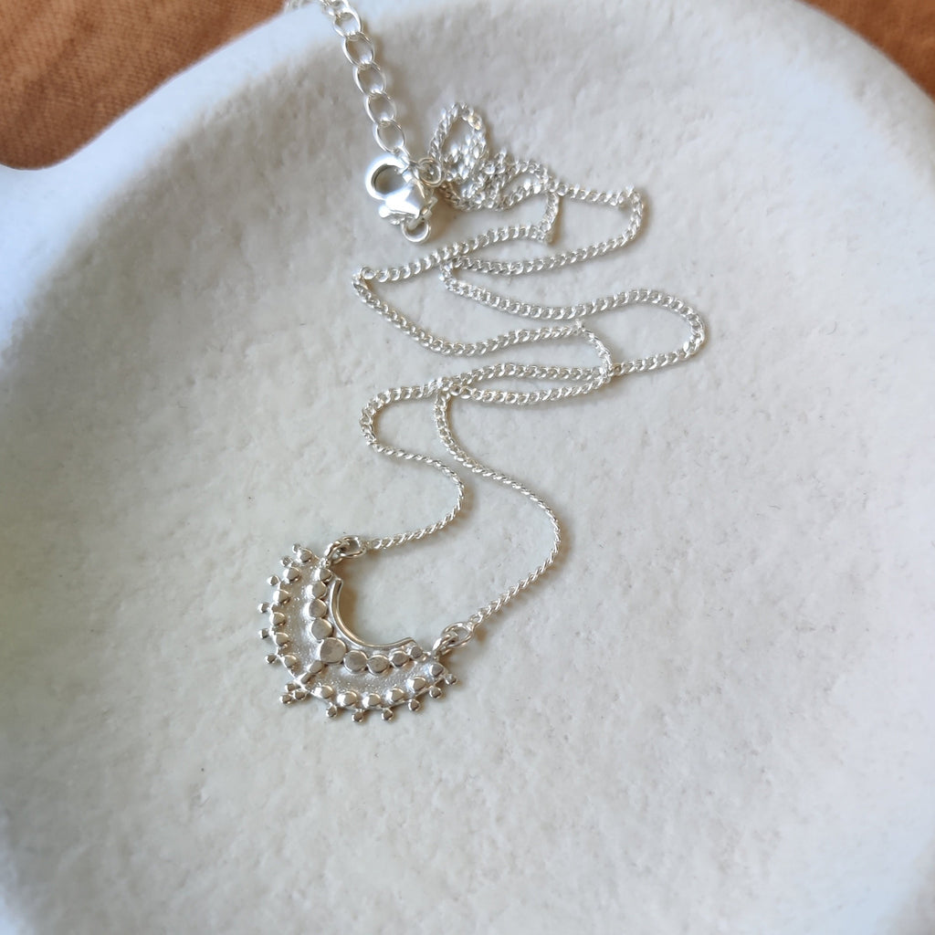 Dainty silver necklace on a white stone surface