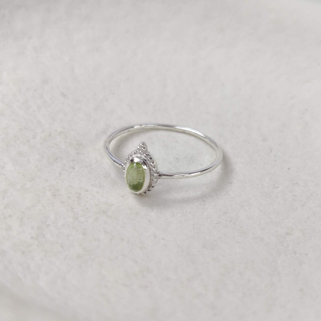 Silver ring with a green gemstone on a white background.