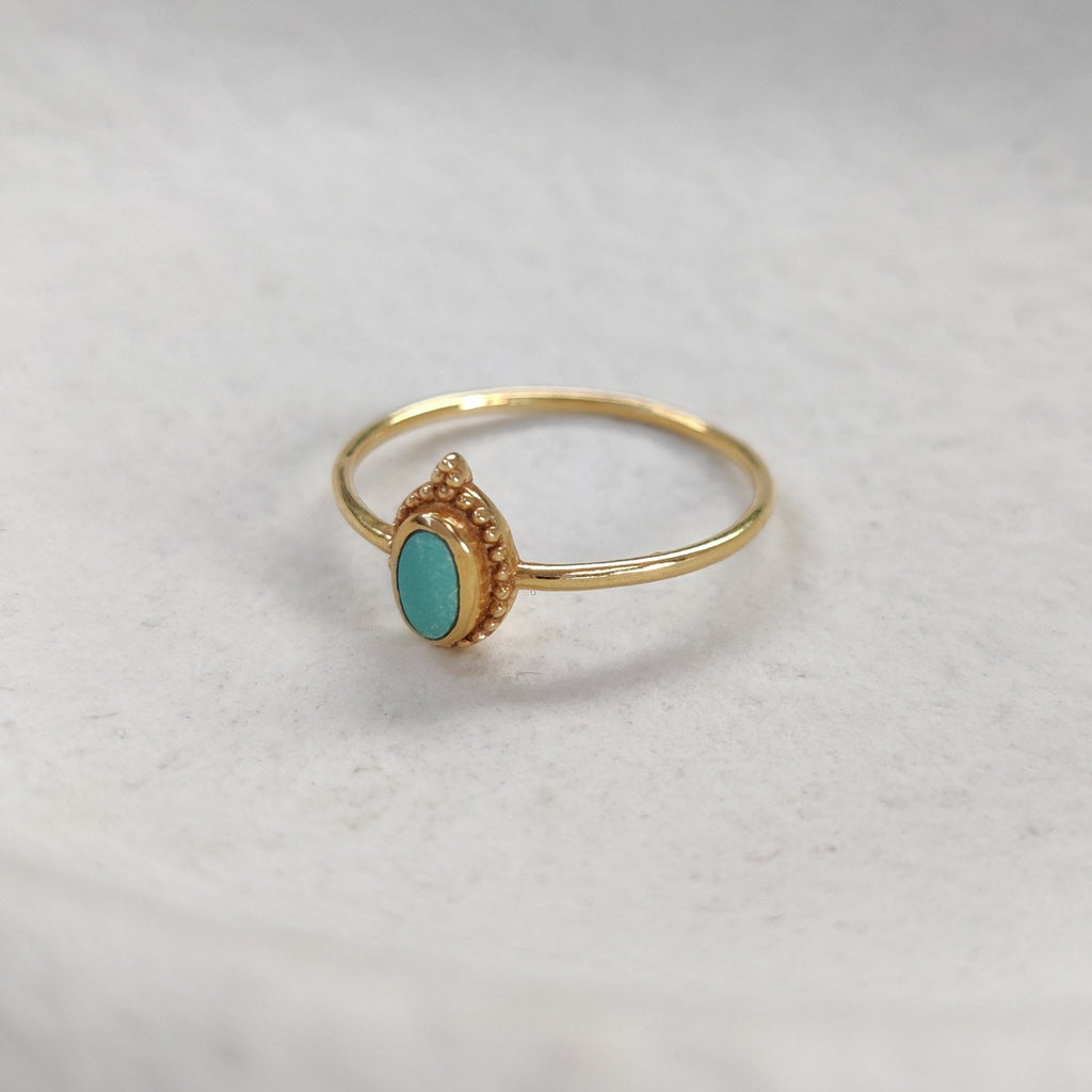 Gold ring with a turquoise stone on a white surface