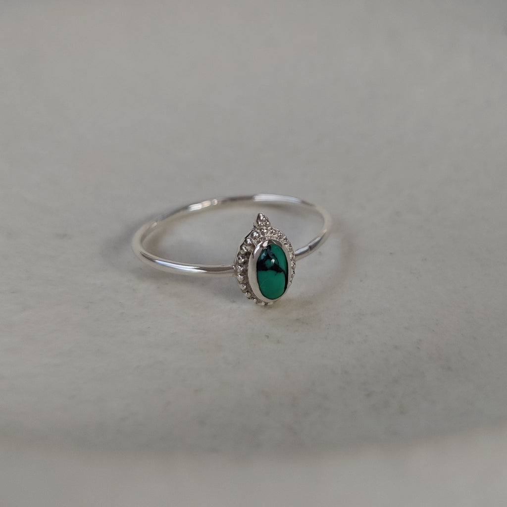 Silver ring with a turquoise gemstone on a light background