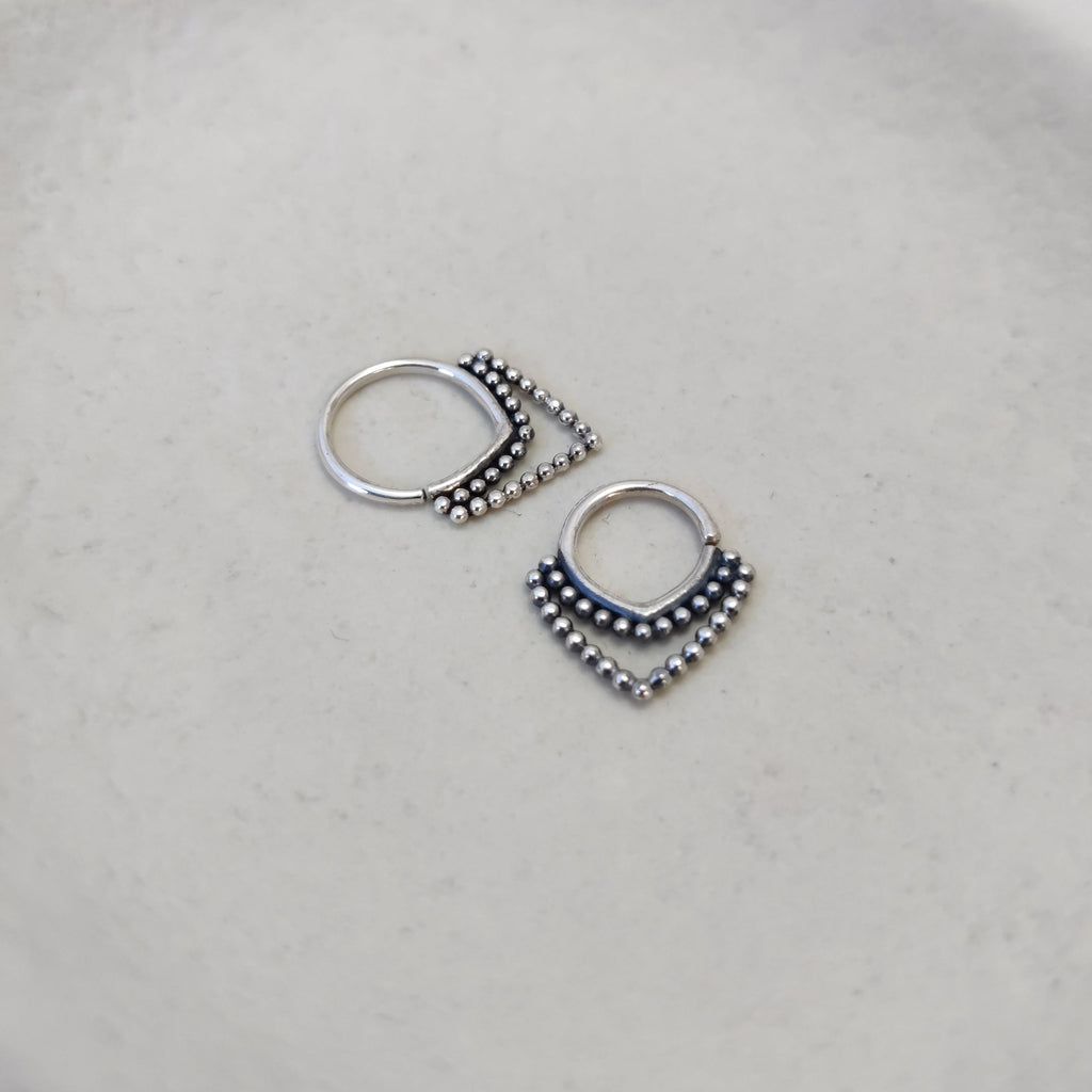 Ornamental silver septum ring with v-shaped design and intricate detailing, highlighting its unique design and craftsmanship. Displayed from different angles, comparing the difference between 8mm and 10mm diameters.