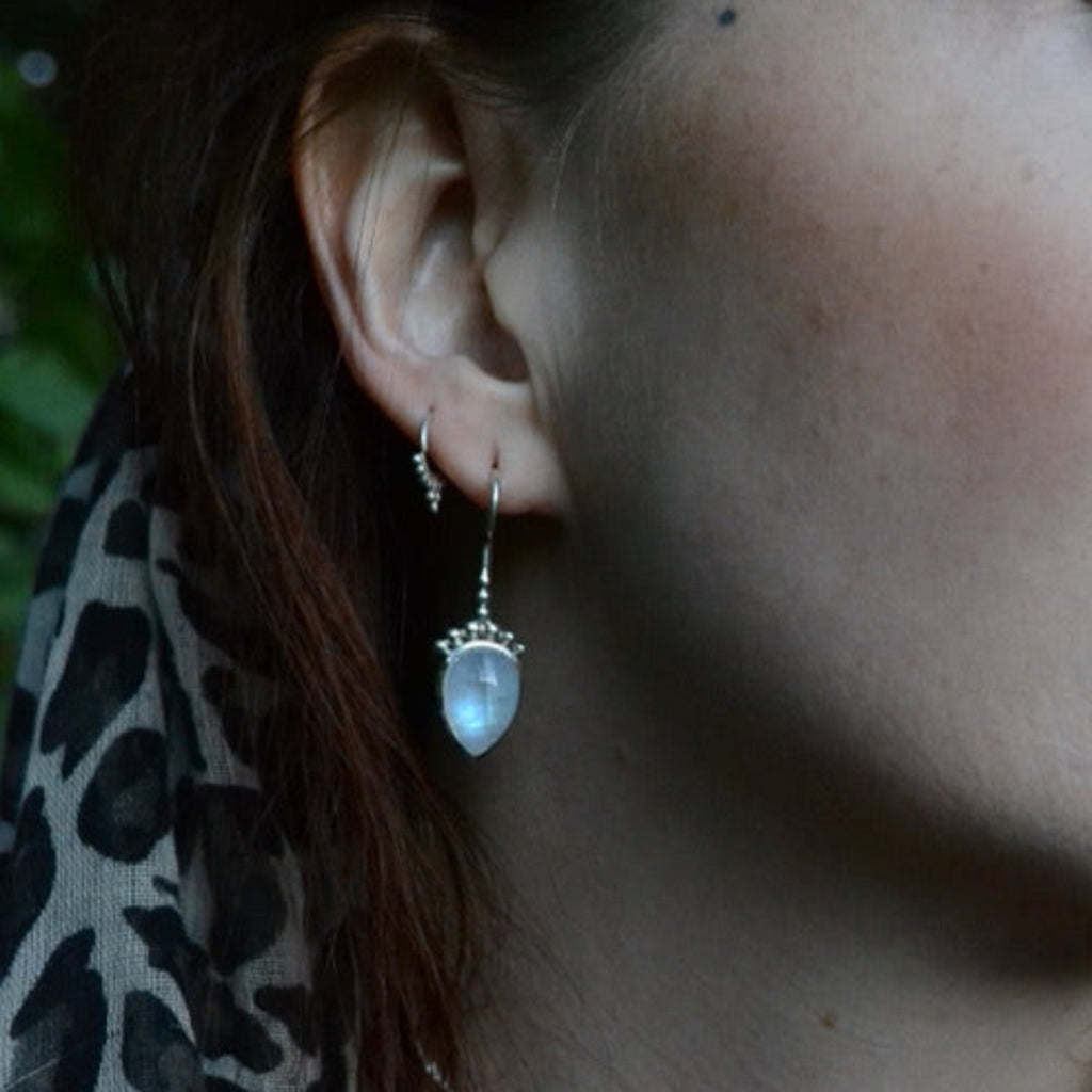 Model wearing silver drop earring with moonstone.