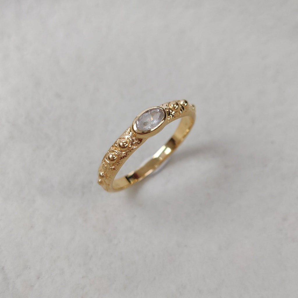 Gold ring with a moonstone  centerpiece on a light background.