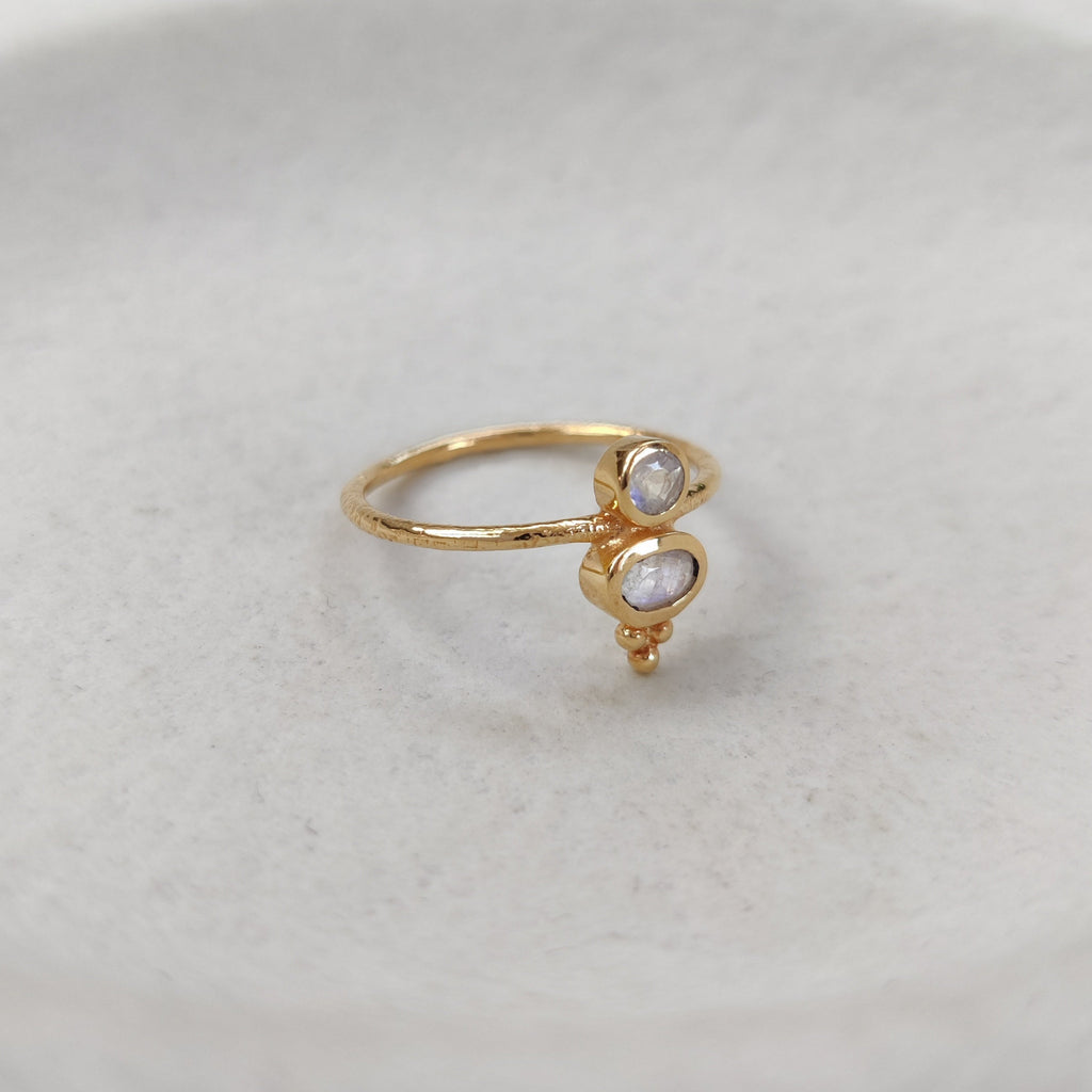 Gold ring with two small stones on a light gray background