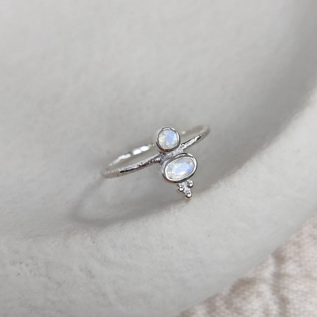 Silver ring with a moonstones on a white ceramic dish.