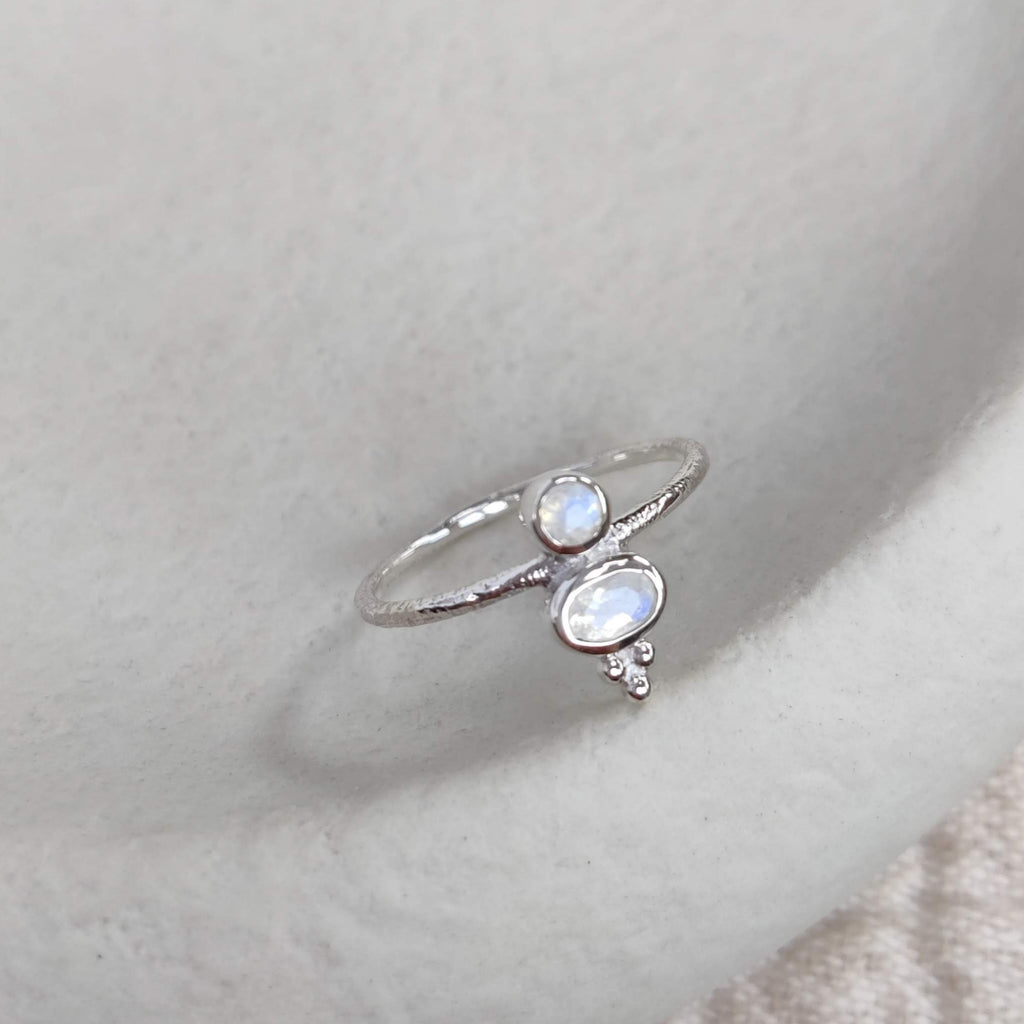 Silver ring with faceted moonstones on a light surface.