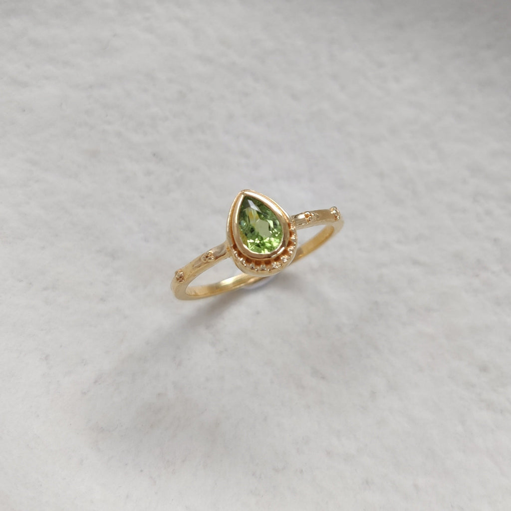 Gold ring with a green gemstone on a white background.