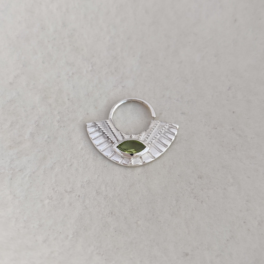 Large silver septum nose ring with a green gemstone on a white background