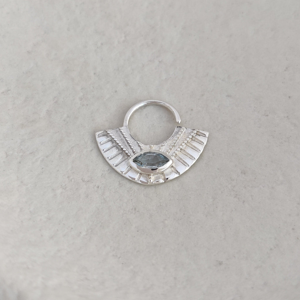 Silver pendant with a blue stone on a textured surface