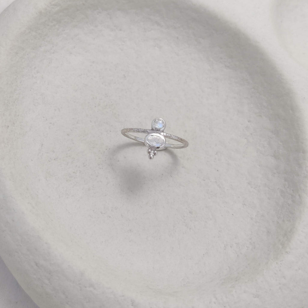 Silver ring with faceted moonstones on a textured white surface