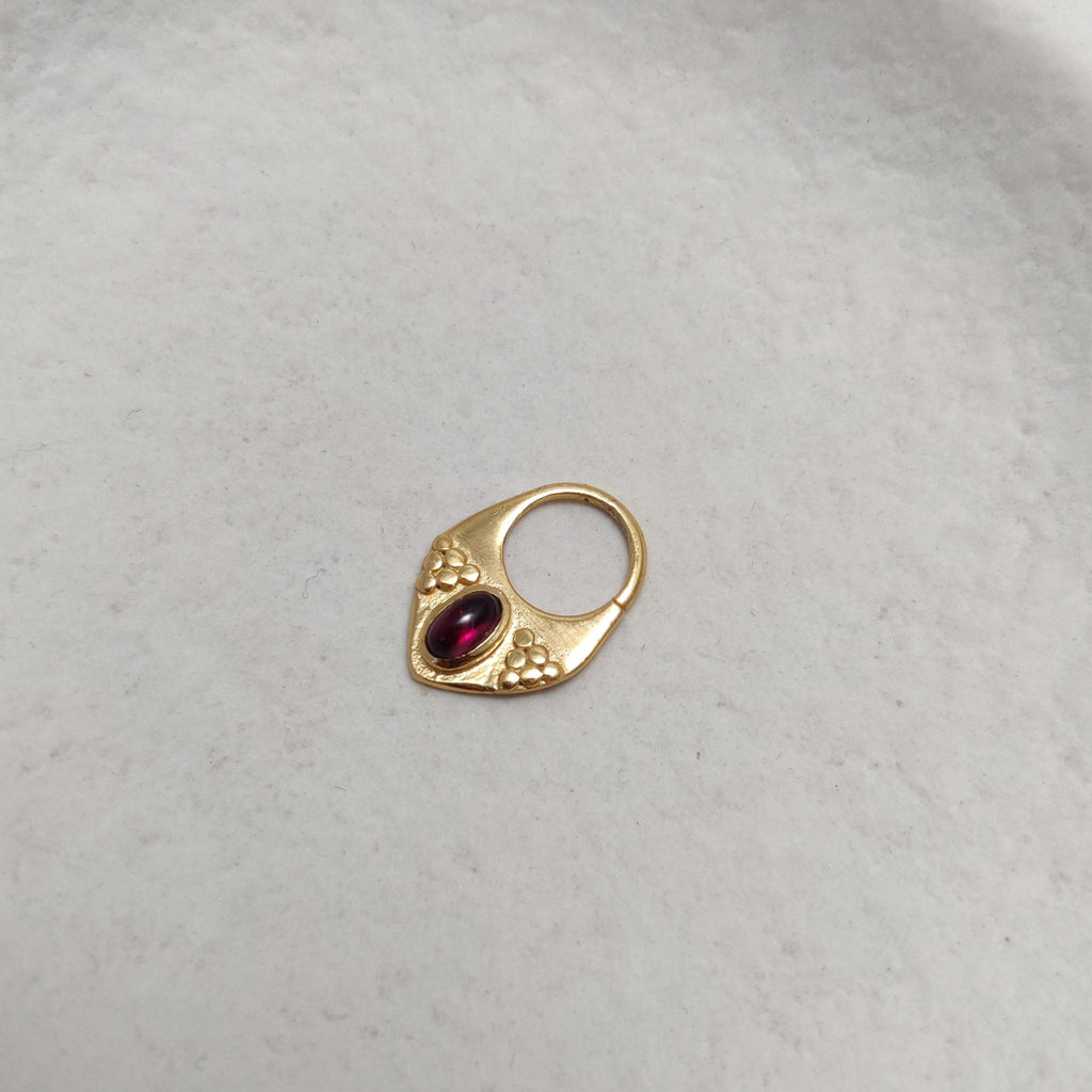 Gold septum jewelry with garnet.