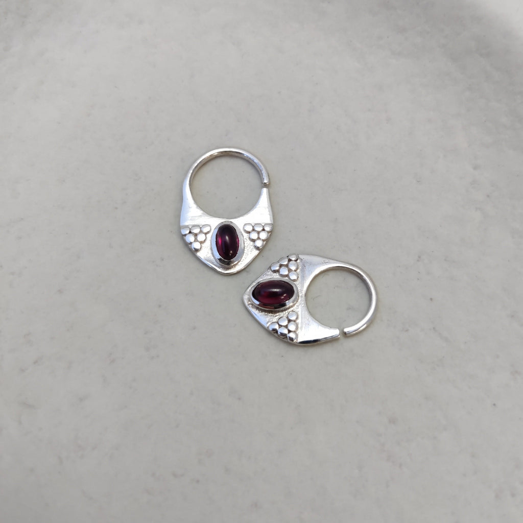 Silver septum rings with garnet, displayed side by side, comparing the difference between 8mm and 10mm diameters and highlighting intricate designs.