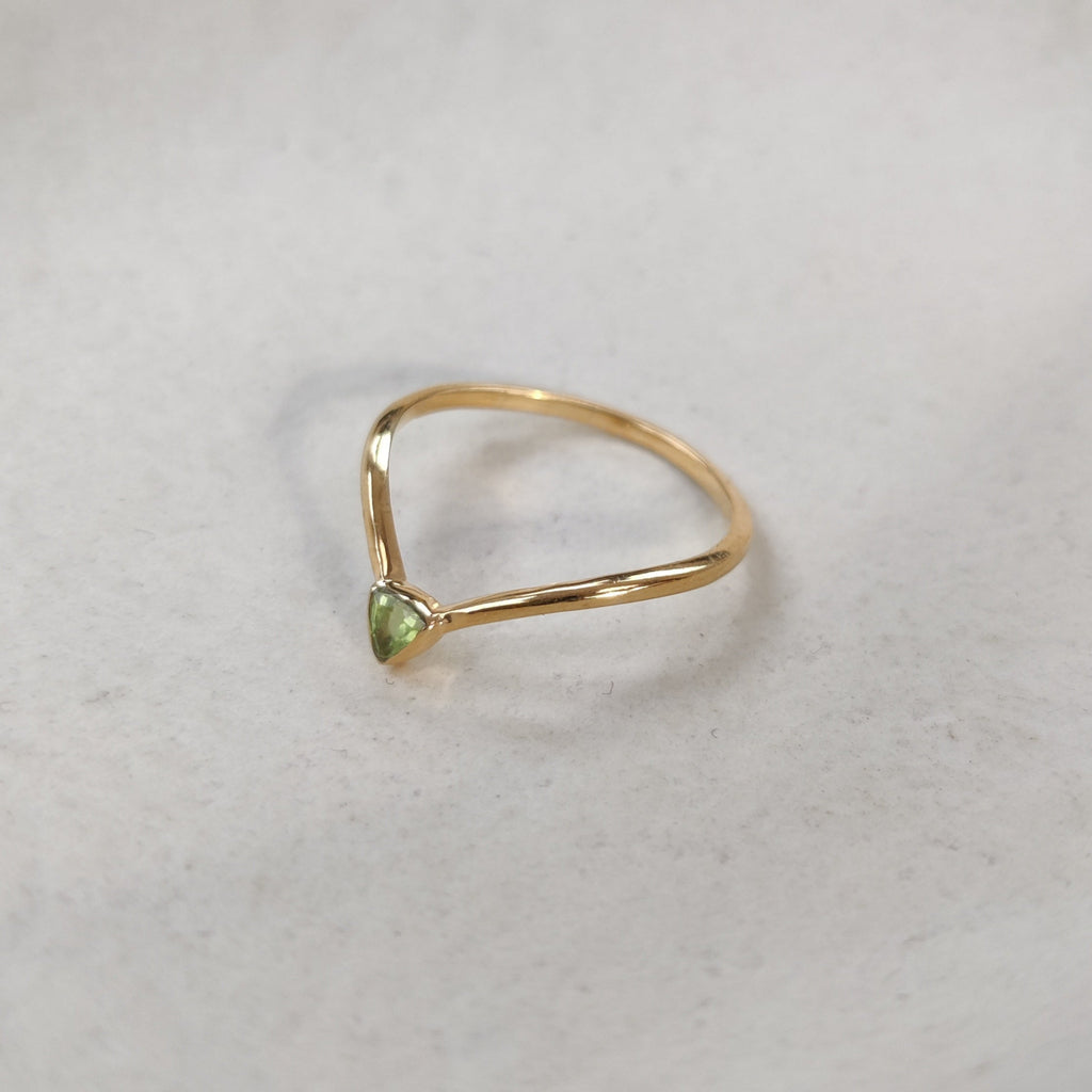 Gold ring with a trillion-shaped green gemstone on a white background