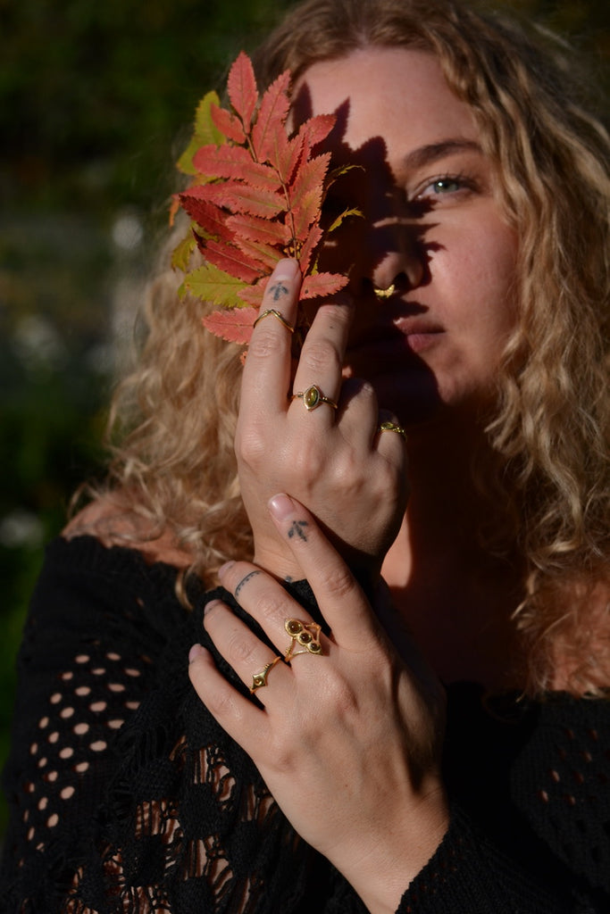 Woman holding autumn leaves over her face with a blurred natural background