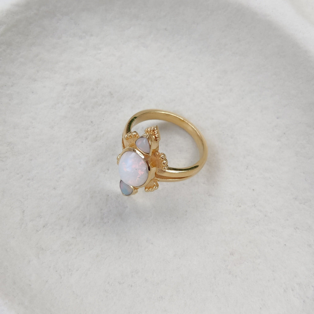Gold ring with a three opals on a white dish.