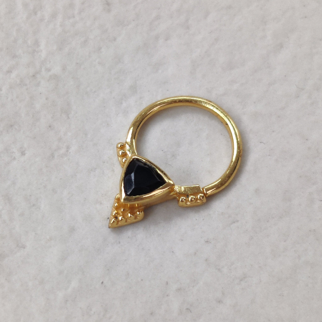 Gold ring with a black onyx gemstone on a light background