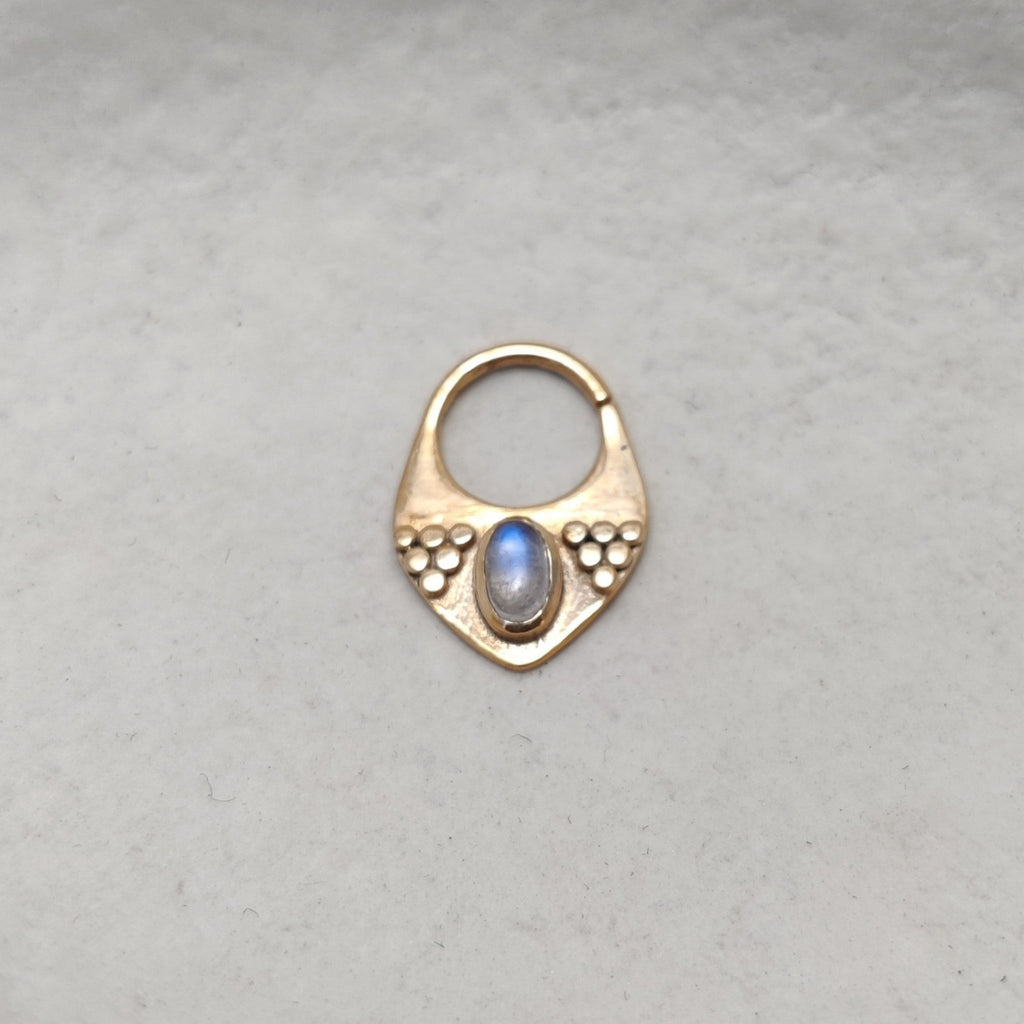 Triangle gold septum with moonstone, displayed on a jewelry plate.