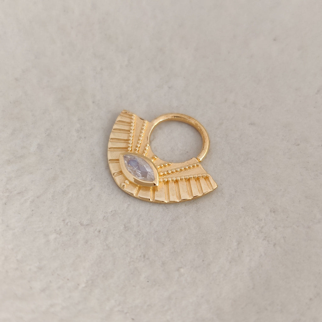 Gold septum nose ring with a moonstone and textured design on a light background.
